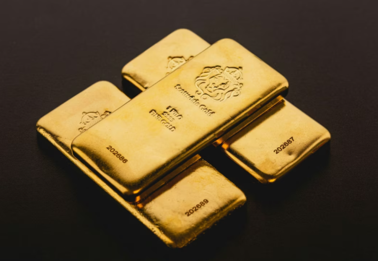 Several 1-kilo Scottsdale Gold bars with lion head emblem and serial numbers, stacked on a dark surface.