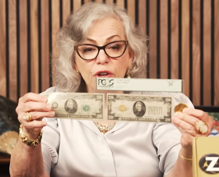 Gray-haired woman in glasses holding up two twenty-dollar bills sealed in plastic grading holders